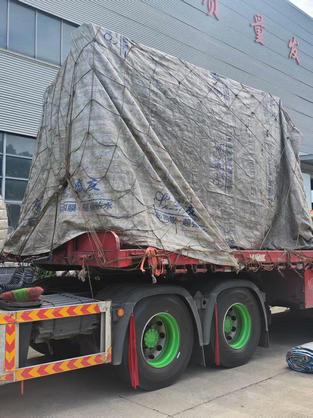 Shipped press brake covered with waterproof tarpaulin and rope net on the trailer, ready for delivery