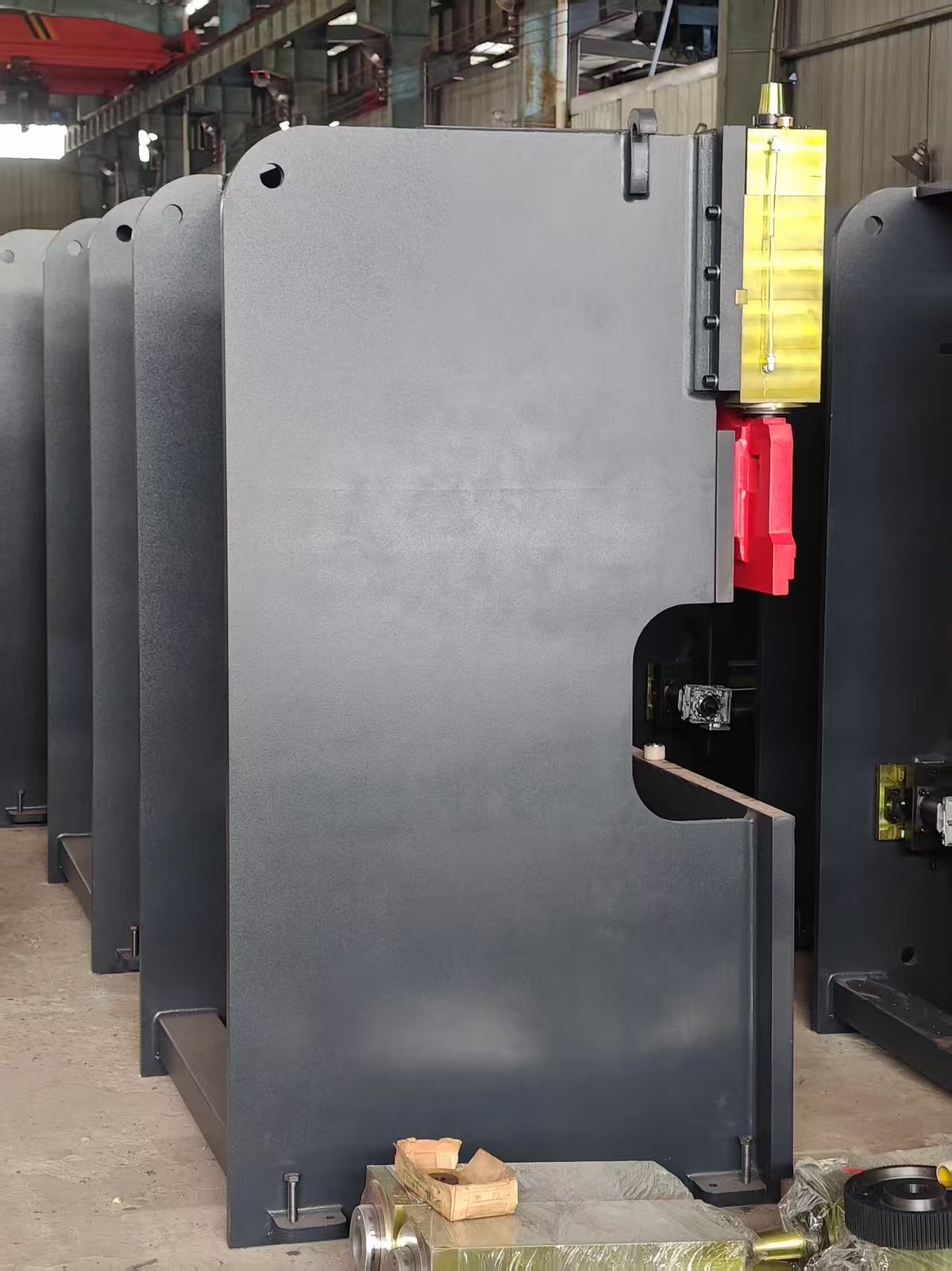 A row of freshly painted grey 50T/1600 press brake frames with yellow ram guide blocks standing in the ZTGAOKE workshop, ready for export shipment