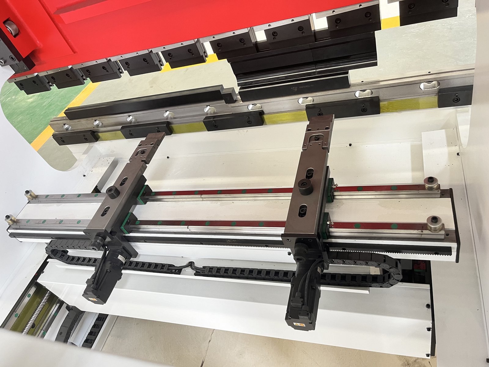 Close-up of the ES-6020 electric press brake backgauge showing linear guide rails, servo motor drives and chain-drive mechanism for precision sheet positioning