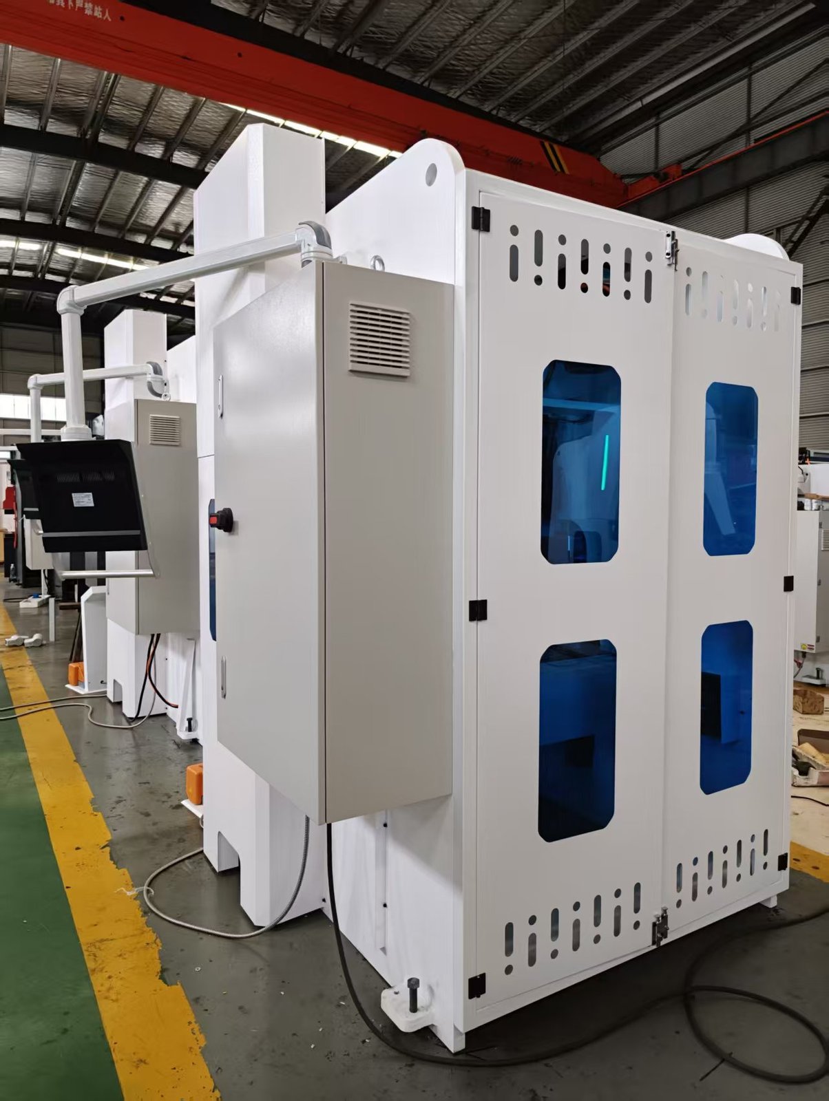 Rear three-quarter view of a new ZTGAOKE press brake inside a fully enclosed white steel safety hood with tinted blue polycarbonate windows, hinged access doors, ventilation slots and a suspended CNC control arm outside the guarding